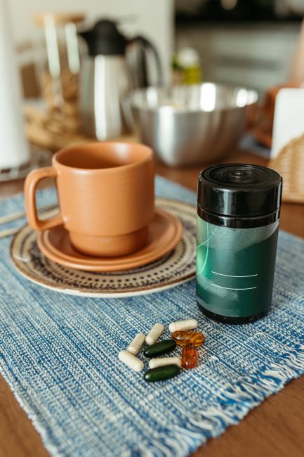 Cozy kitchen scene featuring vitamins and a cup on a wooden table, promoting health and wellness.